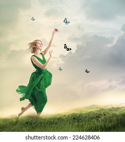 Beautiful girl in a green dress following butterflies on a mountain 