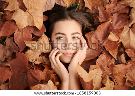 beautiful girl with green eyes lying among the autumn fallen leaves.  posing.  autumn park