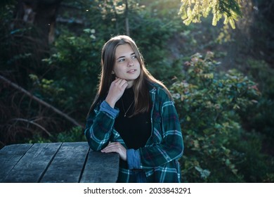Beautiful Girl with Green Plaid Shirt sitting in the Woods at a Wooden Table