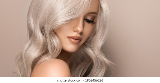 Beautiful girl with hair coloring in ultra blond. Stylish hairstyle curls done in a beauty salon. Fashion, cosmetics and makeup