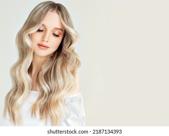 Beautiful girl with hair coloring in ultra blond. Stylish hairstyle curls done in a beauty salon. Fashion, cosmetics and makeup