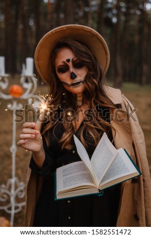 beautiful girl in halloween zombie costume casts a spell in a dark forest
