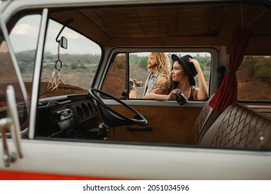 Beautiful girl in a hat with a camera and man with beard, standing by a retro van for tourism, a view from the salon. - Powered by Shutterstock