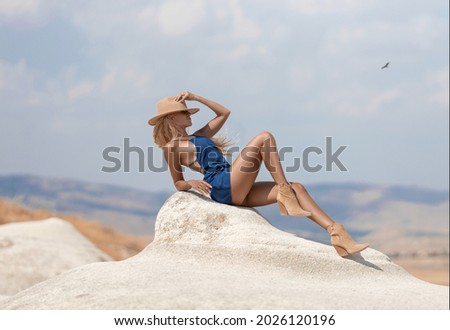 Beautiful girl in a hat and with perfect legs posing in Cappadocia mountain canyon. Traditional nature desert landscape.