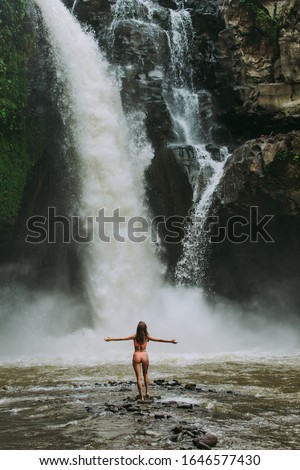 Beautiful girl having fun at the waterfalls in Bali. Concept about wanderlust traveling and wilderness culture