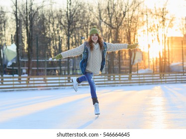 Beautiful Girl Having Fun In Winter Park, Balancing While Skating At Ice Rink. Enjoying Nature, Winter Time