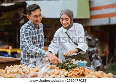A beautiful girl in a headscarf holding a plastic tray to place a selection of side dishes purchased at roadside stalls