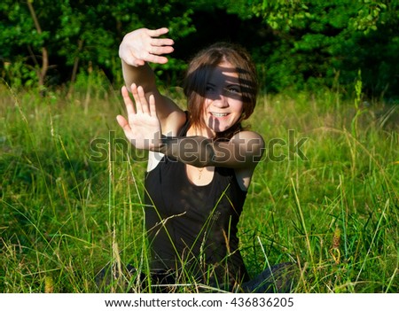 Similar – Junge Frau bedeckt ihr Gesicht vor der Sonne auf einem grünen Feld.