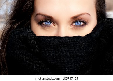 beautiful girl hiding from the wind with a black scarf