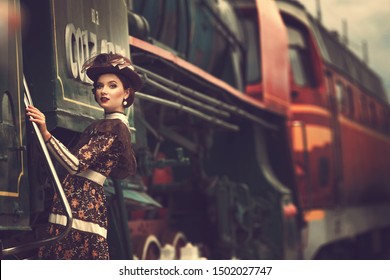 Beautiful girl in a historical retro dress on a background of an old steam locomotive, steampunk,  at the railway station
