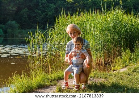 beautiful girl holding a child in her arms on the background of the lake close-up