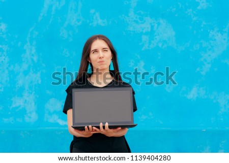 Beautiful Girl Holding a Laptop on a Blue Background. Woman presenting an empty notebook display for advertising purposes 