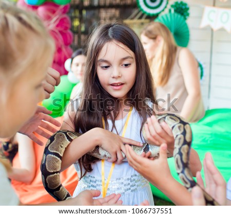 A beautiful girl is holding a python snake on her hands.