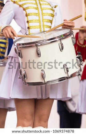 beautiful girl in a hussar uniform play drums at a carnival procession at a flower festival in a city park on a summer day.