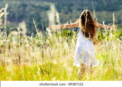 beautiful girl laughs and dances outdoors in a meadow during sunset