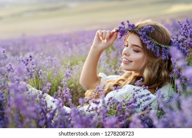 Beautiful girl in lavender wreath and retro dress on the lavender field. Beautiful woman in the lavender field on sunset in France .Girl collect lavender.Soft focus. Series.