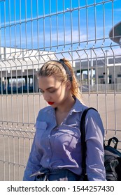 A Beautiful Girl Is Leaning Against A Lattice Gate. Waiting For Release, Transfer To Prison