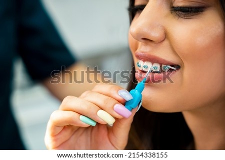 Beautiful girl learning how to use interdental brush at dentist office, side view closeup shot 