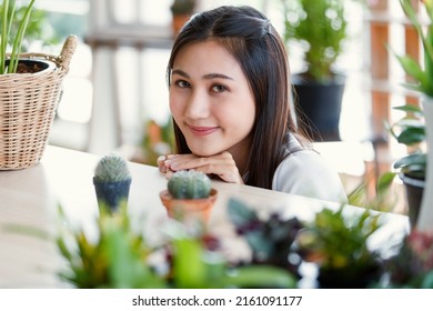 Beautiful Girl Long Black Hair Middle Part Style Charming Eyes Smiling Chin Up Looking At Camera. Surround By Cactus Pot Air Filtering Plants In White Mirror Room. Blur Background. Looks Cute Friendly