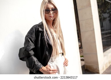 A Beautiful Girl With Long Even Hair Walks Around The City, The Model Is Wearing A Black Braid And White Trousers