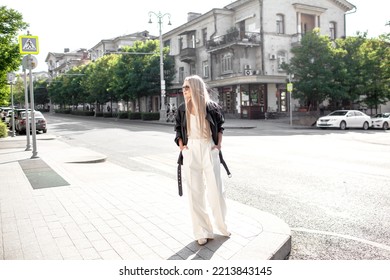 A Beautiful Girl With Long Even Hair Walks Around The City, The Model Is Wearing A Black Braid And White Trousers