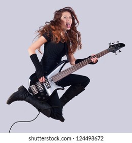 Beautiful Girl With Long Red Hair Playing Bass Guitar And Jumping In The Air.