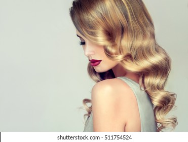 Beautiful girl with long wavy hair .  Blonde with curly hairstyle and red lips