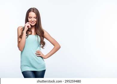 Beautiful girl is looking down with shyness. She is smiling and touching her face with her hand. Isolated on background and copy space in left side