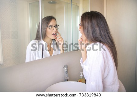 Beautiful girl looking at her skin at the mirror