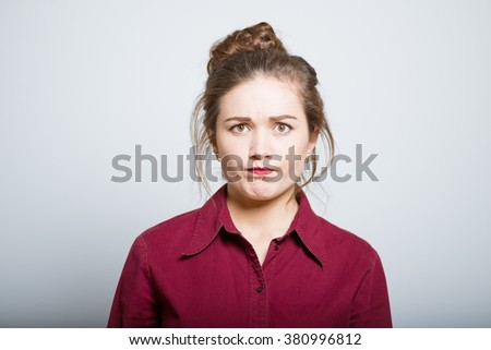 Beautiful girl looks angrily, isolated on gray background