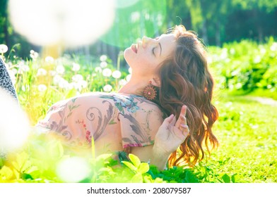 Beautiful girl lying on the grass and enjoying summer time - Shutterstock ID 208079587