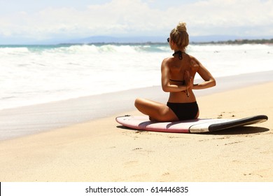 Beautiful girl meditating after surf