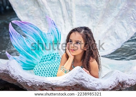 A beautiful girl in a mermaid costume in a large sea shell