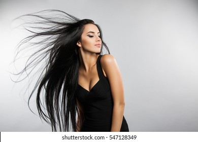 Beautiful girl model with flying the wind hair. A brunette woman in a black dress