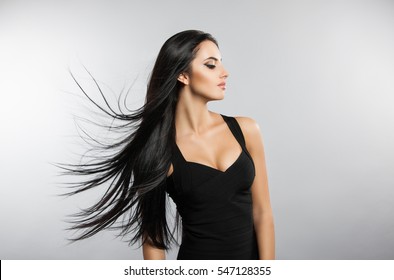 Beautiful Girl Model With Flying The Wind Hair. A Brunette Woman In A Black Dress