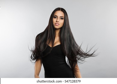 Beautiful Girl Model With Flying The Wind Hair. A Brunette Woman In A Black Dress