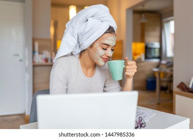 Beautiful girl with morning cosmetics mask drinking coffee - tea and reading newspaper. Summer morning routine. Portrait of a woman with beauty mask on her face