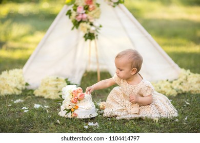 A beautiful girl near a tent decorated with roses smash her first cake