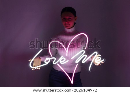Beautiful girl with neon signs. White and pink neon heart with the inscription love me. Trendy style. Wedding design. Neon sign. Custom neon. Home decor. 
