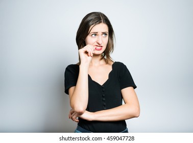 beautiful girl is nervous and bites nails, studio photo isolated on a gray background