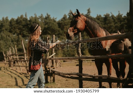 Beautiful girl on the farm feeds the horse. Woman holding farm animals in the forest. Life in the village, a beautiful brunette petting a horse and laughing.