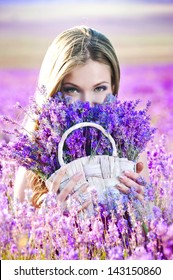 Beautiful Girl On The Lavender Field. Young Woman Collects Lavender In A Basket