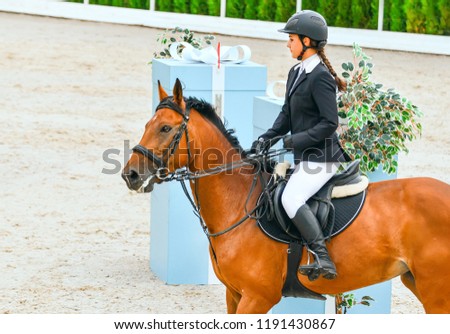Beautiful girl on sorrel horse in jumping show, equestrian sports. Light-brown horse and young woman in uniform going to jump. 