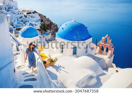 Beautiful girl on summer vacation enjoying breathtaking view of blue-domed church in Oia village on Santorini island Greece Foto stock © 