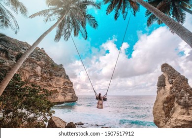 Beautiful girl on swing coconut palms on beach at Daimond  beach, Nusa Penida island Bali ,Indonesia