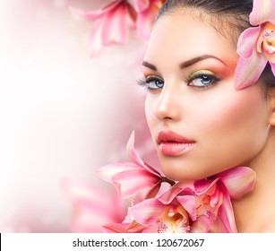Beautiful Girl With Orchid Flowers.Beauty Model Woman Face. Perfect Skin. Professional Make-up.Makeup. Fashion Art