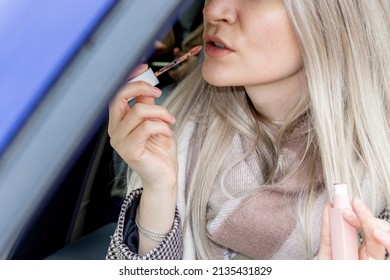 Beautiful Girl Is Painting Her Lips Sitting In A Car And Looking In The Car Vanity Mirror. Blonde Hair Color. Woman Driver. Sun Visor Mirror Clip On. Distracted Driving Awareness Month