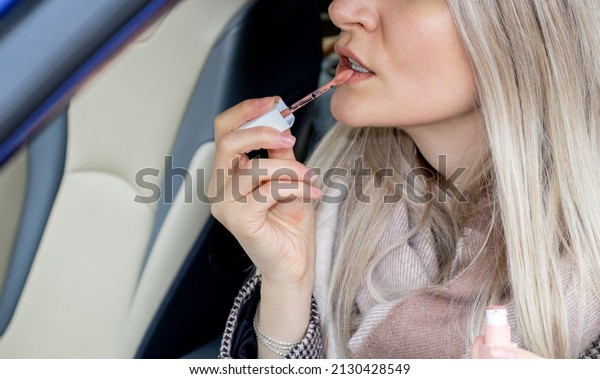 beautiful girl\
is painting her lips sitting in a car and looking in the car vanity\
mirror. blonde hair color. woman driver.  Sun Visor Mirror Clip on.\
beauty and driving car\
concept.