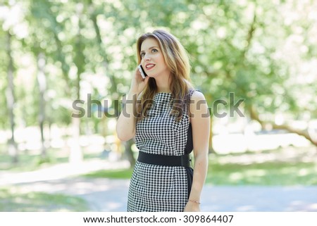 beautiful girl in a park is holding a phone