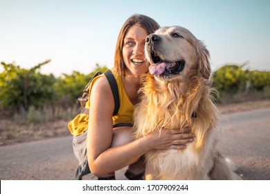 beautiful girl petting golden retriever in a vineyard